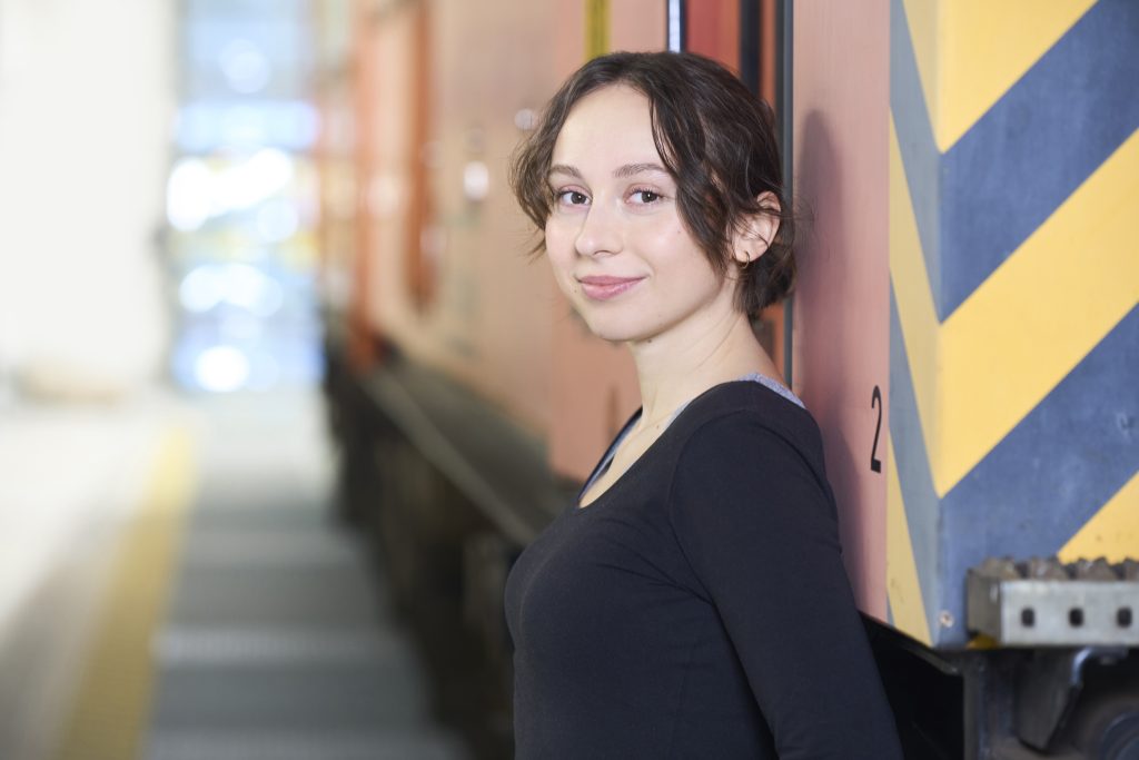 Junge Frau lehnt an Zug und lächelt