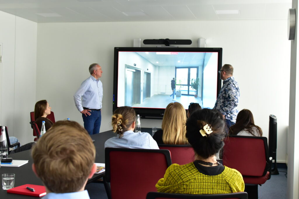 Menschen hören im Besprechungsraum zwei präsentierenden Männern zu