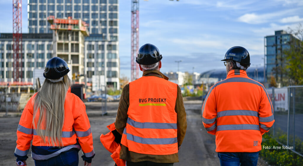 Drei Personen in Warnweste auf einer Baustelle