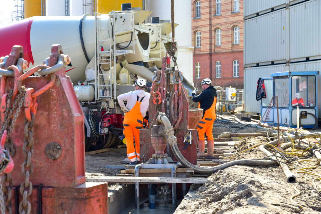 Betonage der Schlitzwände, zwei Männer stehen und überwachen den Prozess.